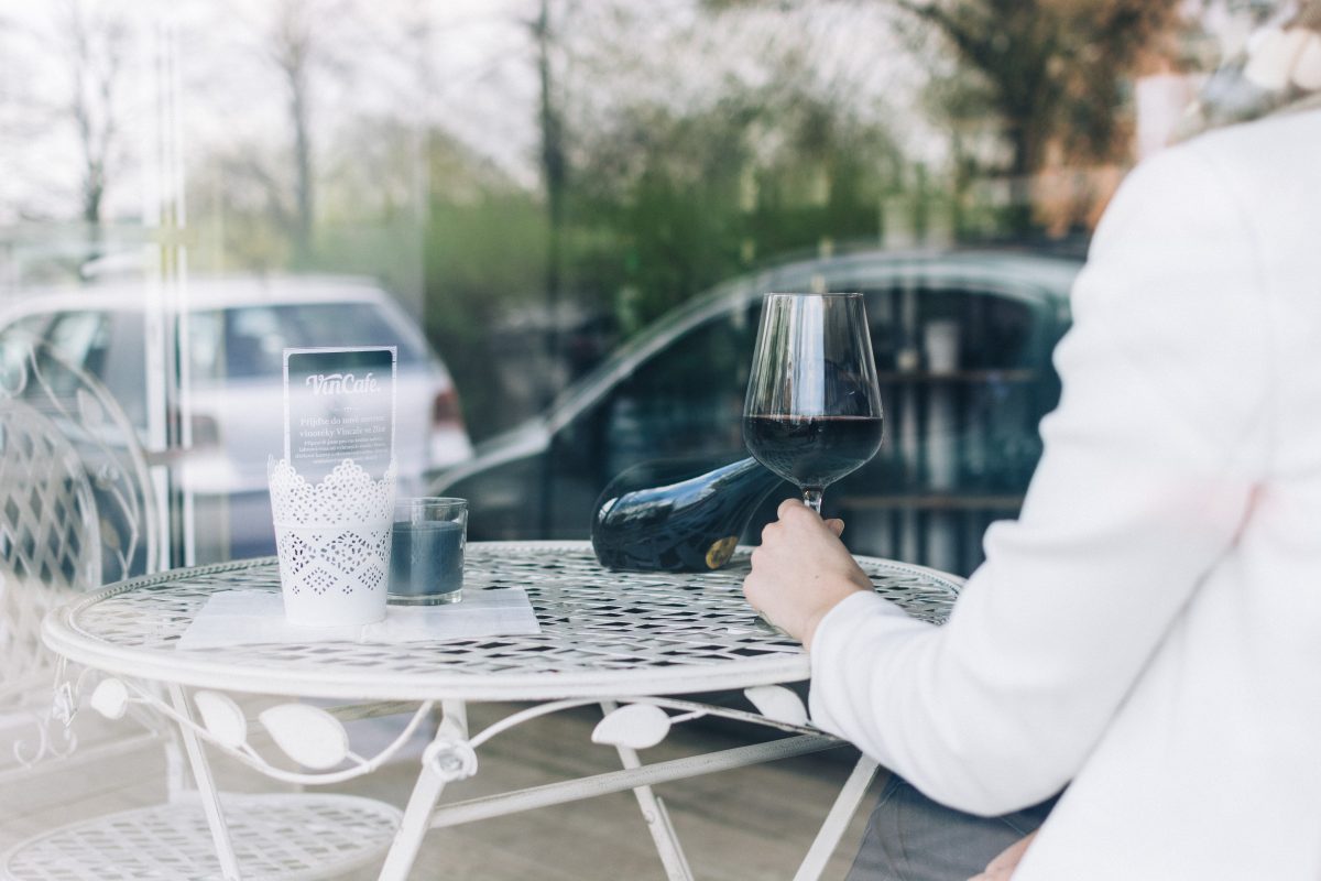 Woman drinking red wine behind a window